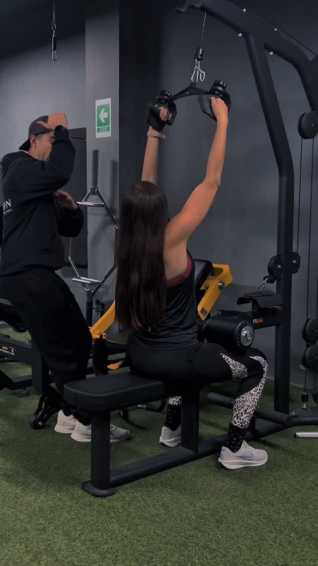 Un coach de Athlon acompaña a una clienta durante su entrenamiento en máquina